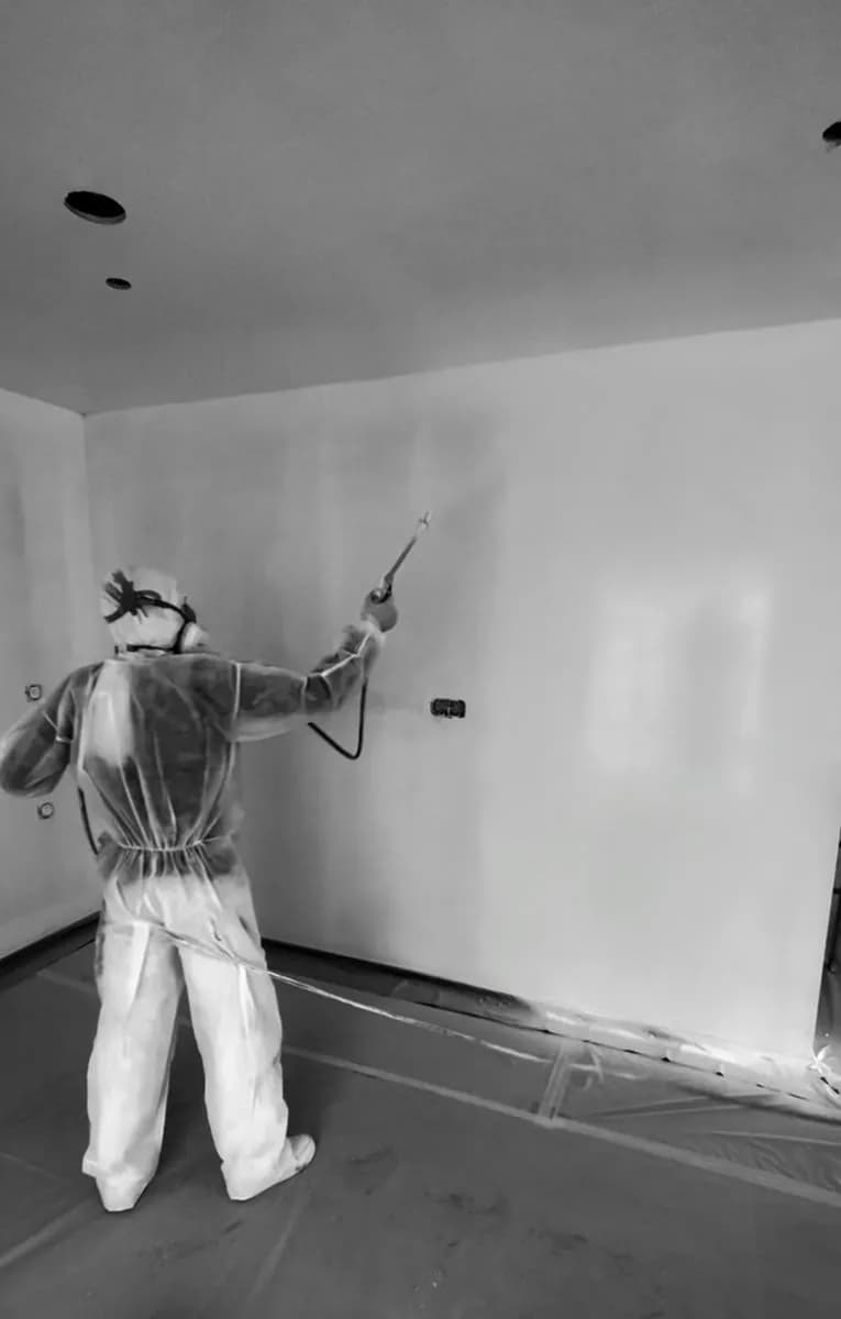 Un peintre de Casa Peinture en combinaison de protection, au pistolet sur un mur